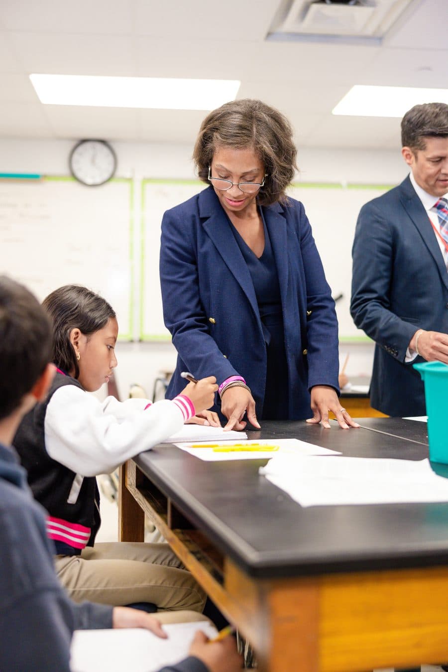 A teacher guiding an elementary student through math work at her desk